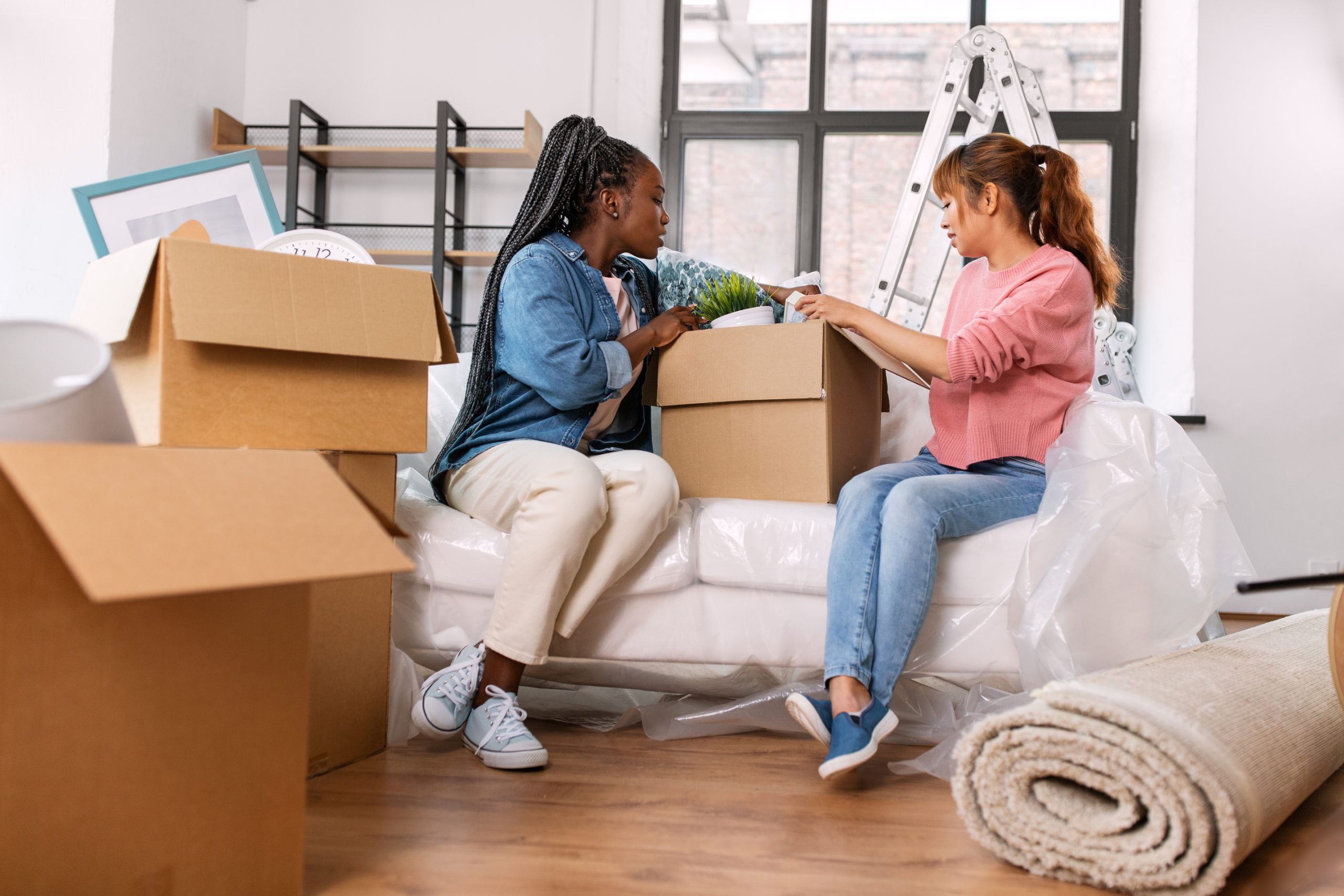 women unpacking boxes and moving to new home to illustrate Are Moving Expenses Deductible