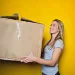 Woman Moving Box to illustrate how to choose a reputable moving company and how to pack for moving an apartment