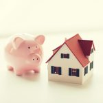 close up of house model and piggy bank to illustrate Cheapest Moving Company Rates Find the Most Affordable Move