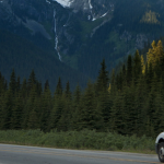 A moving truck on a lonely highway with trees and mountains in the background to help illustrate best way to move out of state.