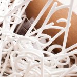 Pile of white plastic clothes hangers in a box close-up