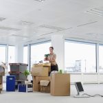 a woman places a potted plant on a pile of items to be moved to illustrate office moving company near me