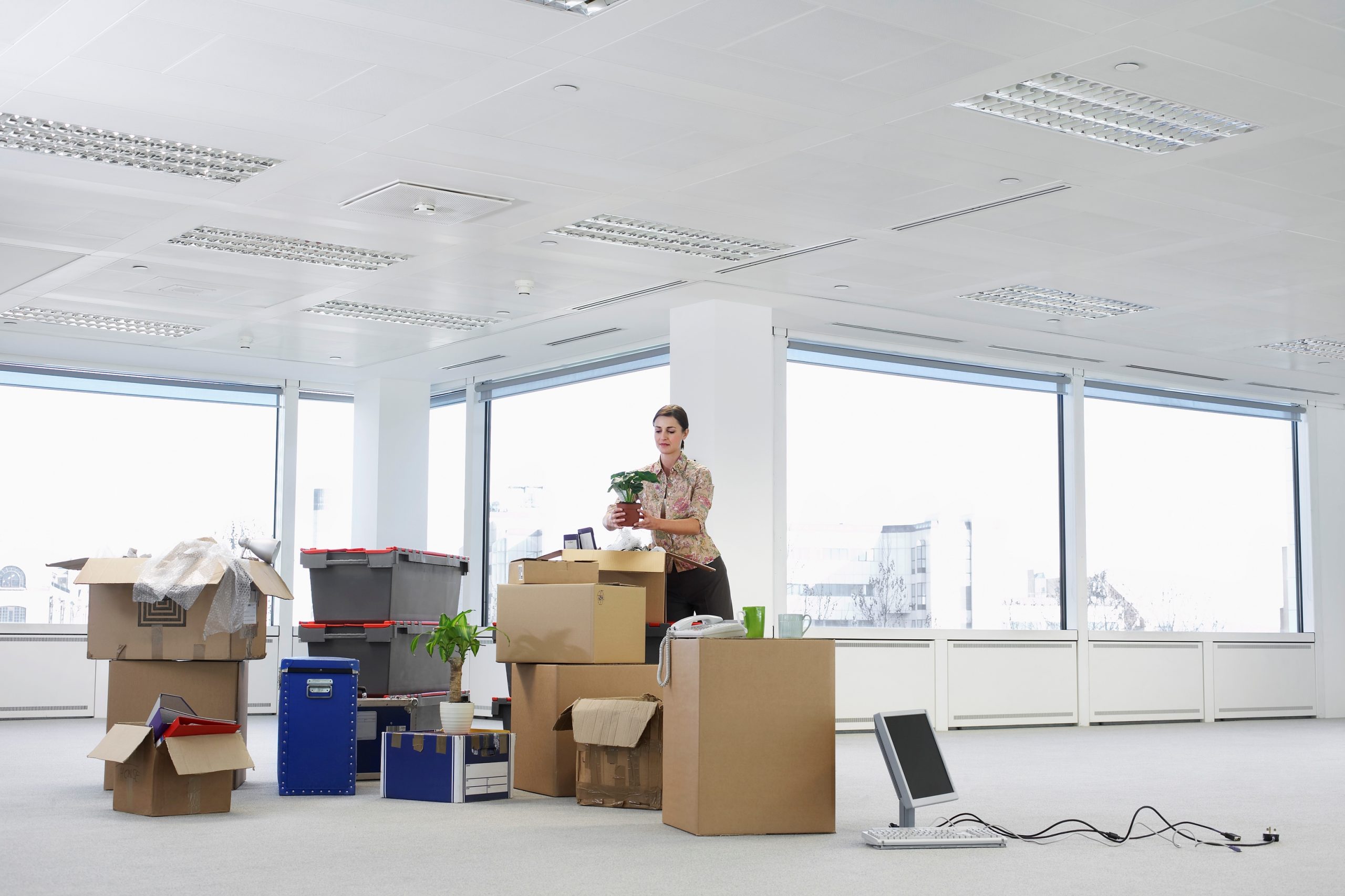 a woman places a potted plant on a pile of items to be moved to illustrate office moving company near me