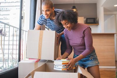 Young black couple unpacking at their new house to illustrate Questions To Ask Movers And Packers