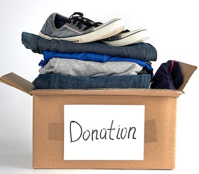 folded clothes and shoes in a brown donation box to illustrate Where to donate clothes in Portland OR