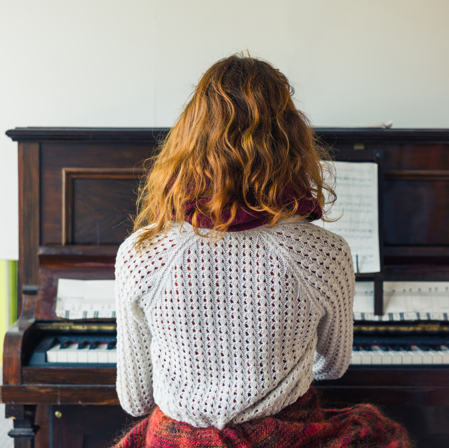 Woman sitting at a piano from behind to help illustrate Tigard moving services